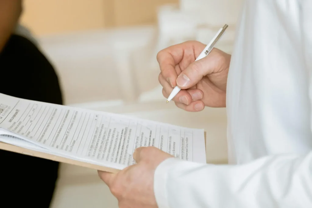 Close-up of a healthcare provider writing on a medical clipboard.
